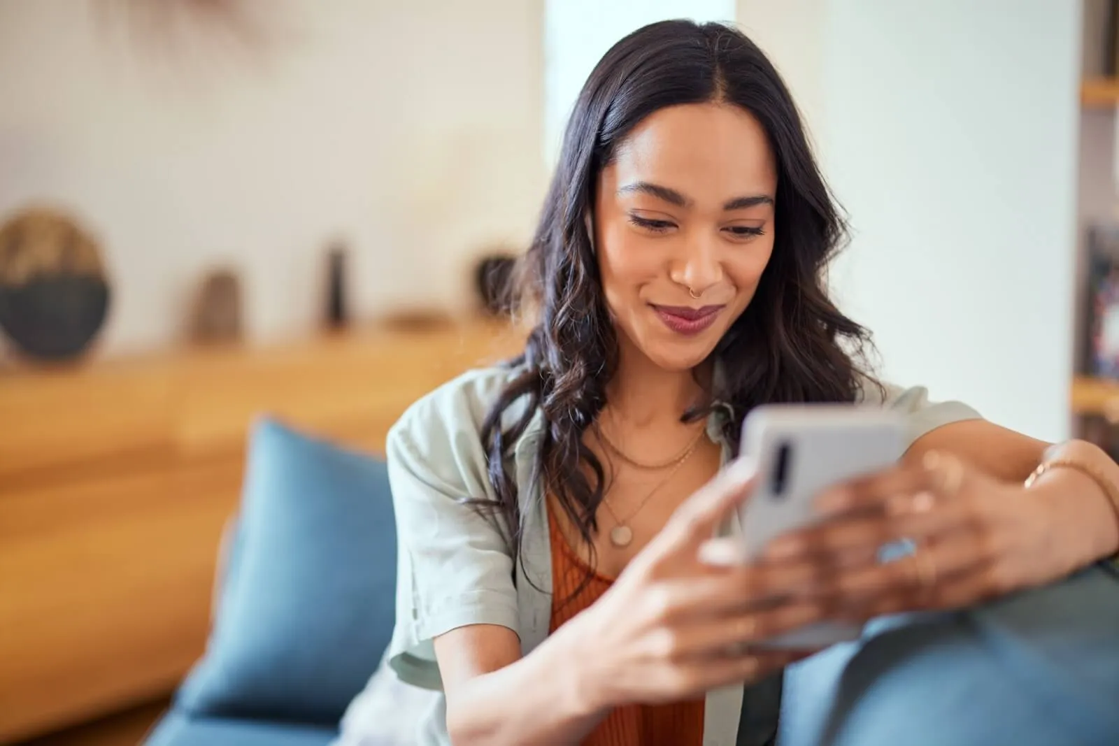 Person relaxing on couch while checking phone, wearing casual attire in home setting